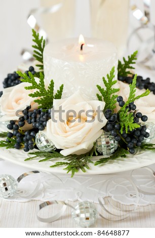 Christmas table decoration with roses,winter berries and candle
