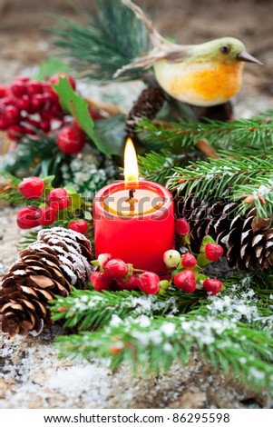 Christmas decoration: fir sprig,candle, cones and berries in snow
