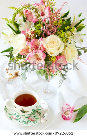 beautiful flowers in vase , cup of tea and biscuits