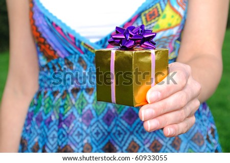 Young woman holding a gift in hand. outdoor.
