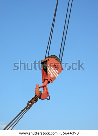 one red crane arm with rusty metal cables on blue sky. robust industrial jib concept