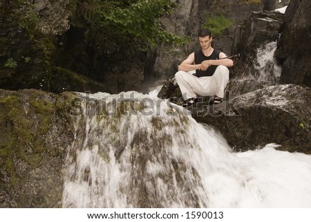 Water falling and rolling around, rest after teaching. Man rests on a rock after hard fencing.