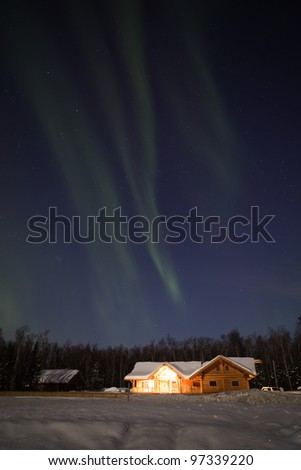 Weak Aurora Borealis over log house in Alaska