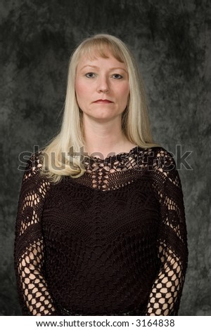 beautiful middle aged woman posing in front of portrait backdrop