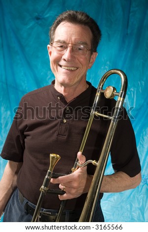 mature man posing with trombone in front of portrait backdrop