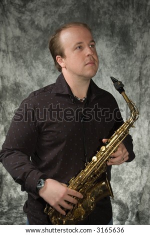 young balding man posing in front of portrait backdrop with saxaphone