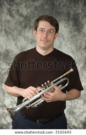 young man posing with trumpet in front of portrait backdrop
