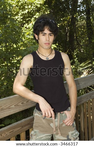 handsome young male model outside on a boardwalk leaning on the railing