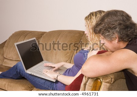 Man and woman relax on the couch with laptop