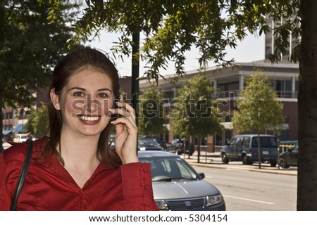 Pretty girl talks on the cell phone as she walks down the street.