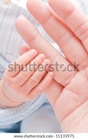 newborn baby\'s tiny hand grasps mom\'s little finger