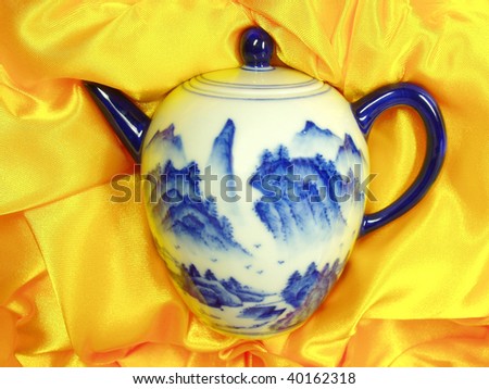 Ceramic Teapot is lying on golden gift packaging material