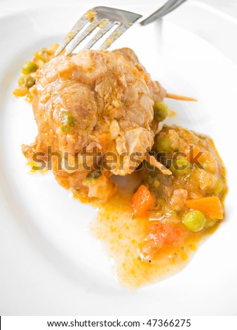 Meat roulade and vegetable soup with fork on white dish.