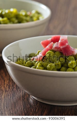 Peas with bacon in terracotta bowl.
