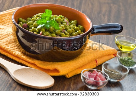 Peas with bacon in terracotta bowl.