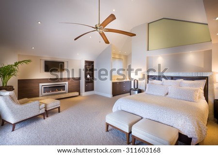 Spacious double bed bedroom with a wooden fan photographed in daytime light