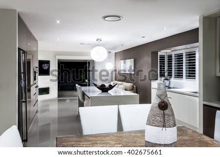 Modern dining room with the kitchen focusing ornamental items like  a vase illuminated by lights at night