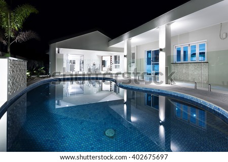 Clear blue water round swimming pool of a modern hotel or house at night with flashing lights
