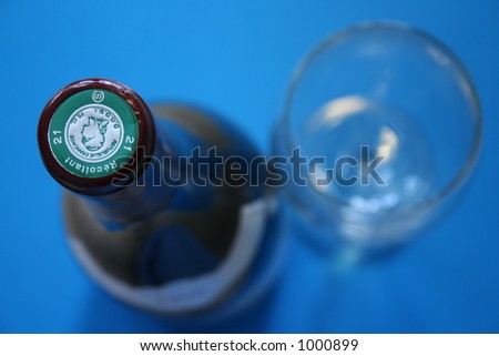 Top view of a wine bottle and blue background. Shallow DOF. Focus is on the generic cork label.