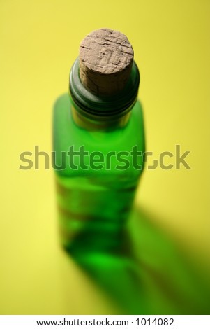 Green bottle with a cork attached with special lighting effect and shadow. Focus is on the cork.