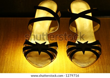 Pair of golden shoes. Shallow DOF. Focus on the front bow of the left shoe.