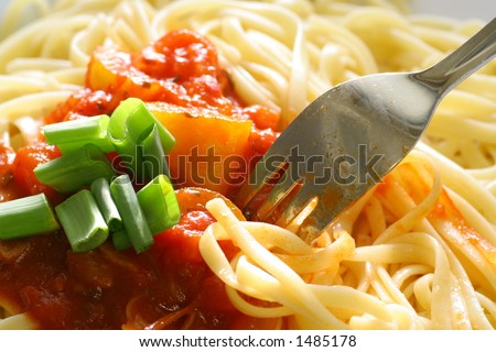 Plate of spaghetti with tomato sauce and a fork digging in.