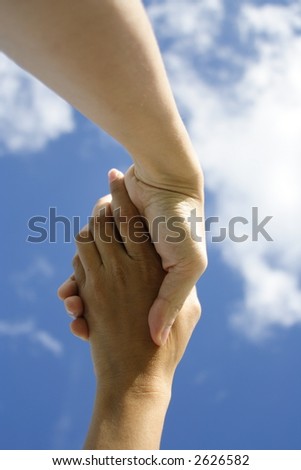 A pair of hands holding or shaking each other against a blue sky. Concept: Agreeement reached or helping hand.