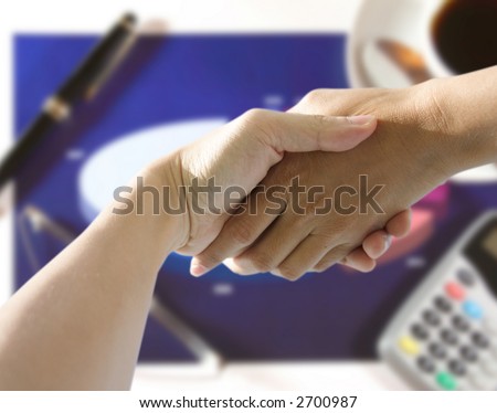 A pair of hands holding or shaking each other against a business background. Concept: Business deal done.
