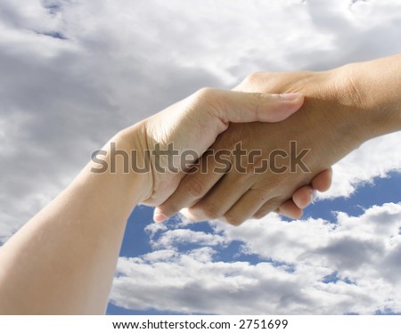 A pair of hands holding or shaking each other against a cloudy background. Concept: Business deal done.