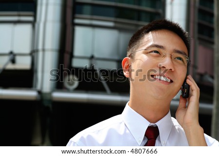 Good looking asian business man talking into a hand phone.