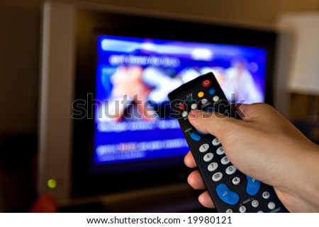 Hand pointing a tv remote control towards the television.