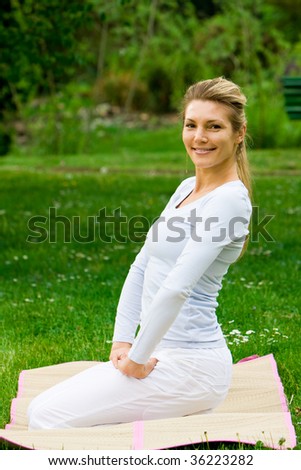 Blonde girl in nature green park exercising yoga, fitness program