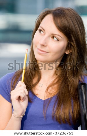 Pretty beautiful caucasian white girl pondering or thinking outside college school holding pencil