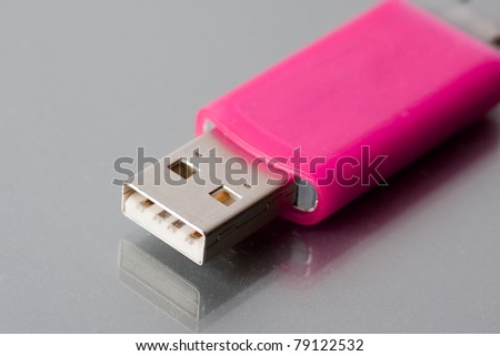 Small portable USB flash disk drive in pink with reflection