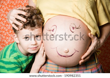 The child clung to a pregnant belly, which painted eyes and mouth.