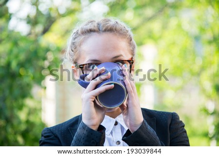 Girl in glasses with blue drink a cup of coffee.  Girl in glasses with blue drink a cup of strong tea.