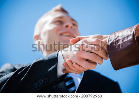A man in a business suit shaking hands with a client after a successful transaction
