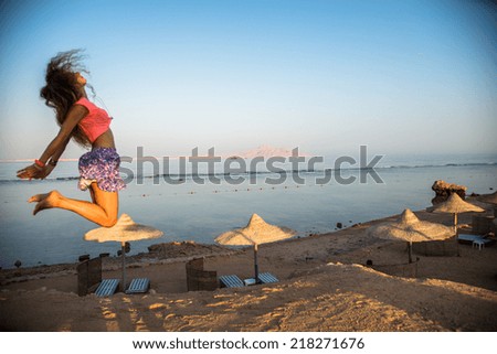 Girl jumps high on the sandy beach background