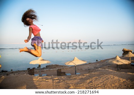 Girl jumps high on the sandy beach background