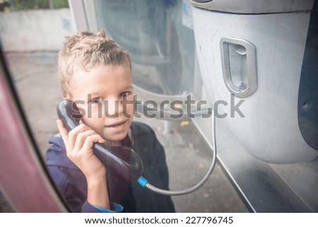 Child dials a phone number in a phone booth