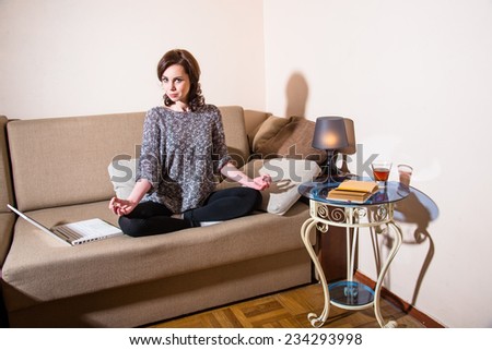 Girl sitting in the lotus position and meditates on the couch