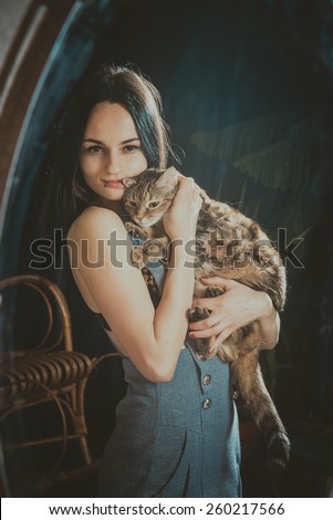 A girl holds a cat and looks at herself in the mirror