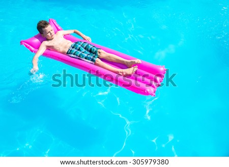 A boy floats on an inflatable mattress in the pool