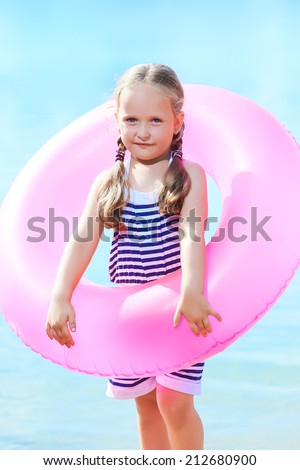 happy little girl and swim ring at the beach