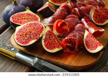 dried jamon slices with figs on wood table