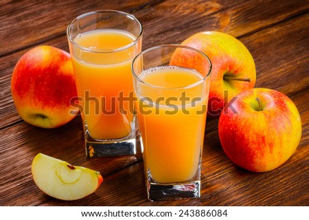 Two glasses of Apple juice and apples on wooden table. Selective focus