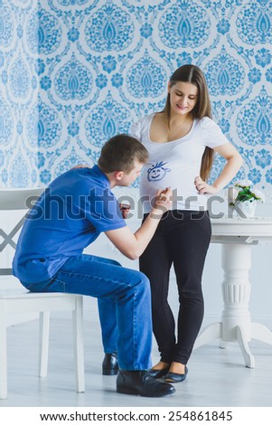 happy man draws on his belly pregnant wife