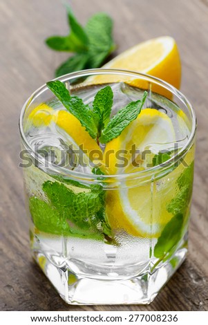 Lemon coctail drink. Lemonade in two glass and lemon with mint on the table