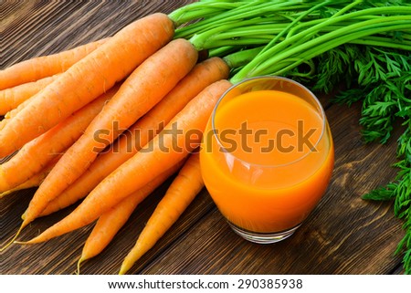 Carrot juice in glass and vegetables beside
