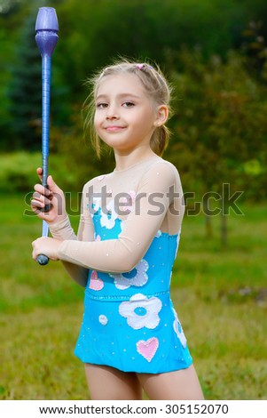 fitness, sport, people and healthcare concept - little sporty girl exercising with gymnastic mace over park background